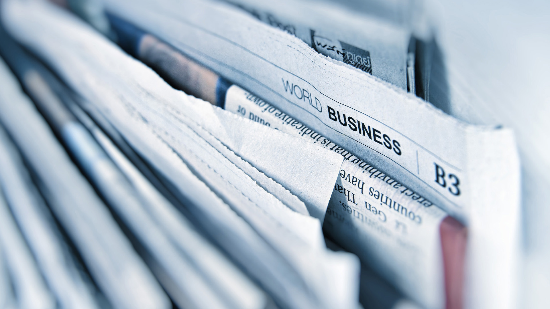 Stack of newspapers focused on a "World Business" section headline, representing global economic and financial news.