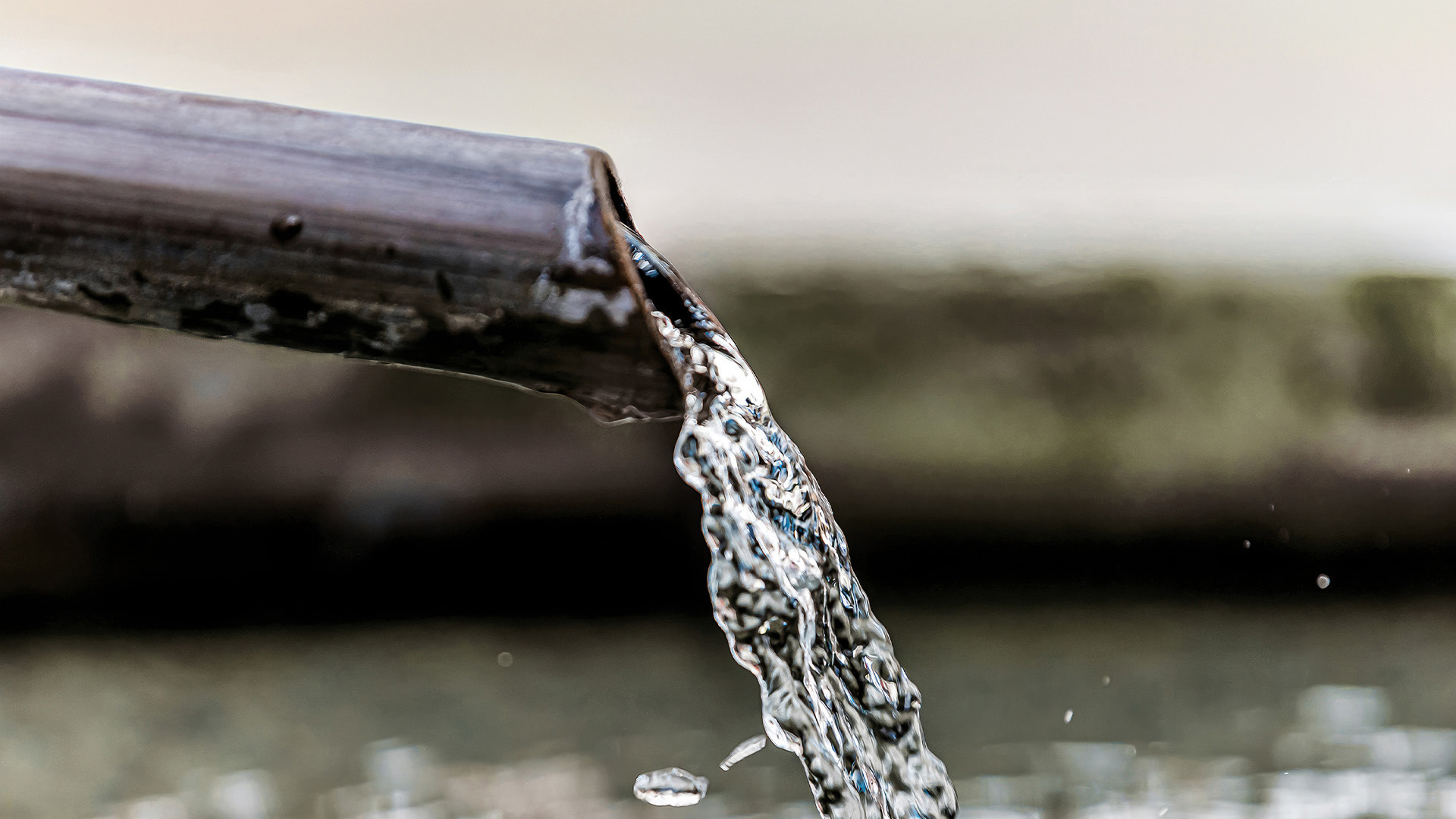 Close-up of water flowing out of a pipe, illustrating water shut-off operations.