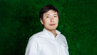 Tolegen Sadvakassov, Business Development Manager, posing in front of a green textured background wearing a white shirt.
