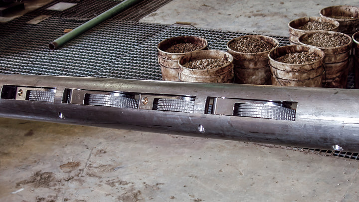 Tool used for milling composite frac plugs on coiled tubing, shown on the rig floor beside containers of debris and equipment.