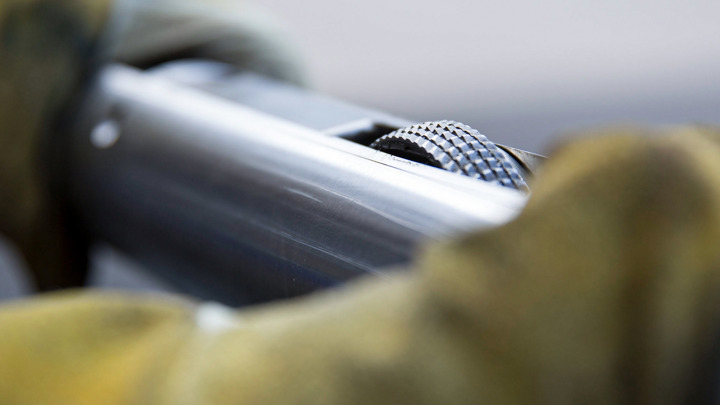 Close-up of a gloved hand holding a Well Cleaner RCB tool, used to prepare the wellbore for plug and perf operations.