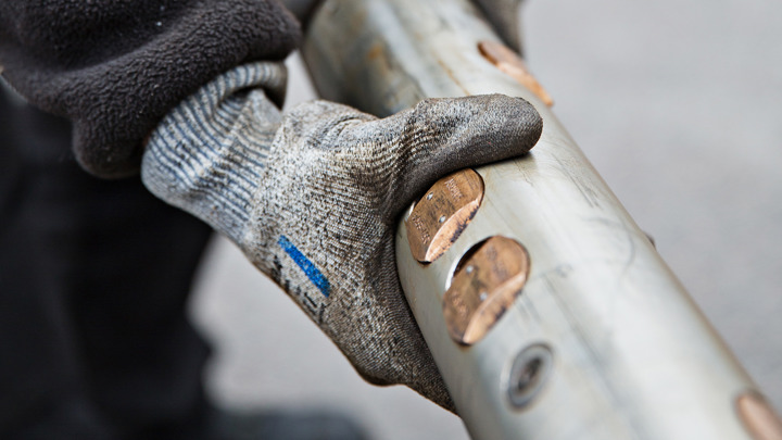 Gloved hand inspecting a Well Stroker® tool with deployed anchoring slips used for removing a stuck isolation sleeve in Alaska.