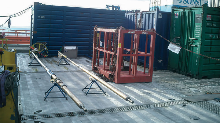 Wireline equipment laid out on rig deck for setting an upper completion packer, with containers and tools arranged for offshore operation.
