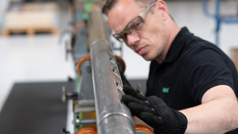 An engineer inspecting a wellbore tool with precision, ensuring its quality and readiness for operation in the Welltec workshop.