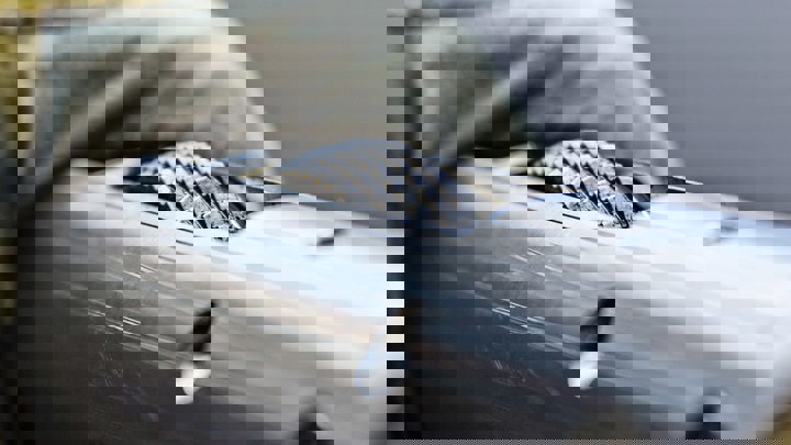 Gloved hand holding a metallic downhole tool with a textured roller, used in well intervention operations.