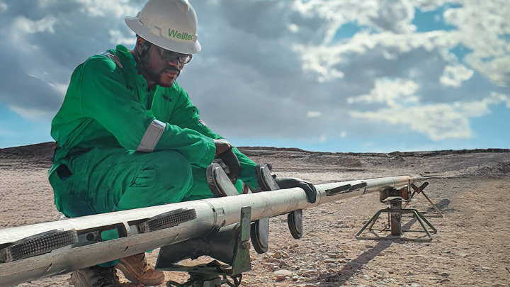 Engineer working on a pipe during an offshore operation under the bright sky, wearing protective gear.