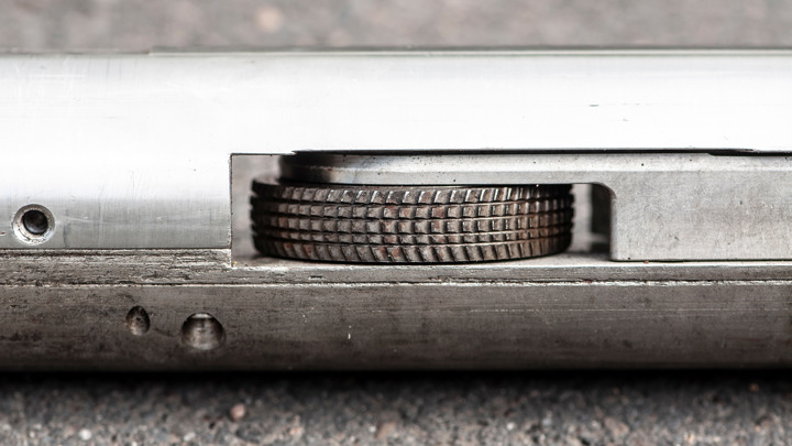 Close up of a metal wheel tool embedded in a cylindrical steel housing used for mechanical operations in wellbore environments.