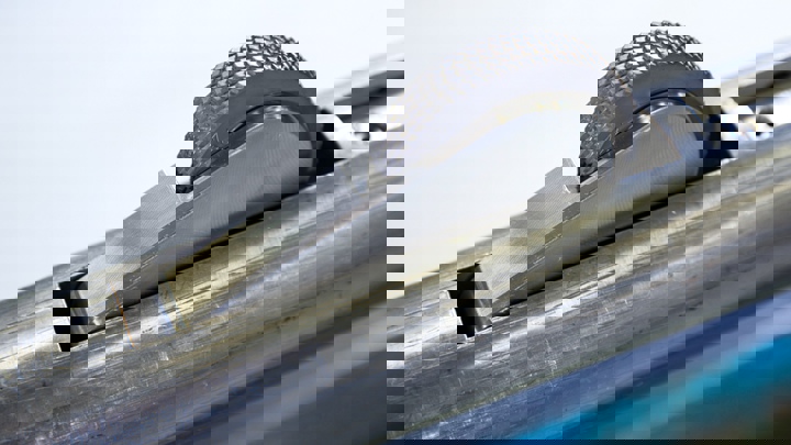 Close up of a Welltec tractor tool wheel with a knurled surface, partially extended from a metallic housing, used for traction inside wellbores.