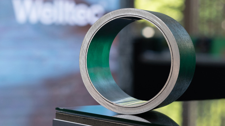 A close-up of a metallic Welltec tool component, showcasing its ring-like structure with a green interior, used in wellbore applications.
